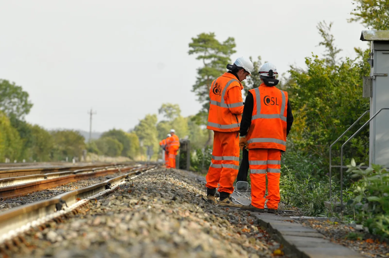 Two OSL engineers on the lineside, with a team working further along the track
